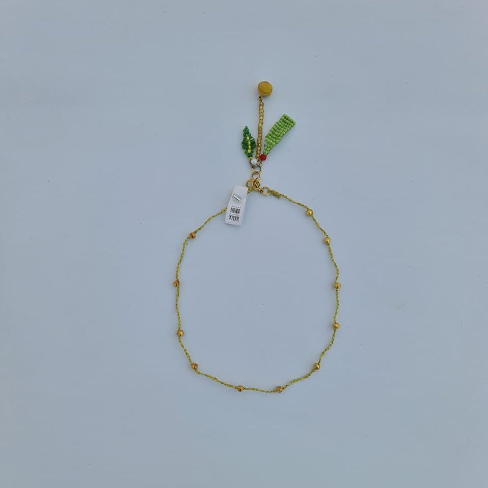 Gold bracelet with small beads on a light gray background