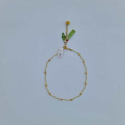 Gold bracelet with small beads on a light gray background