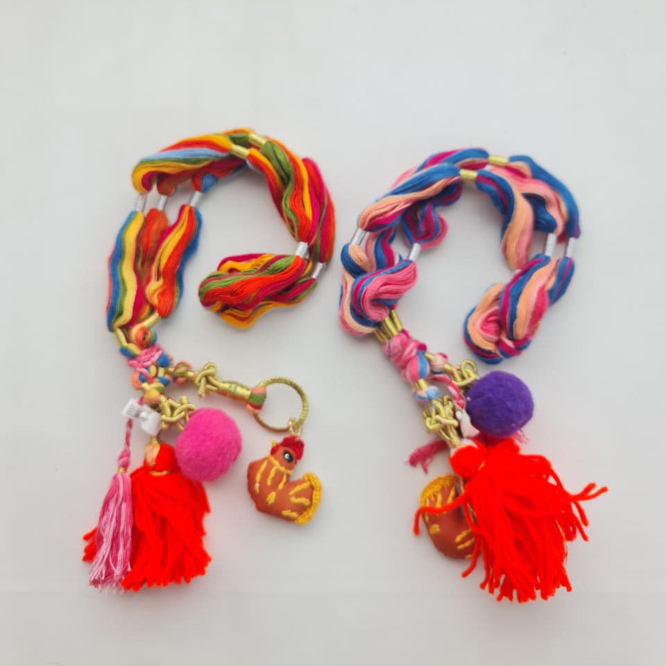 Two colorful braided yarn keychains with tassels and charms, displayed on a plain white surface.
