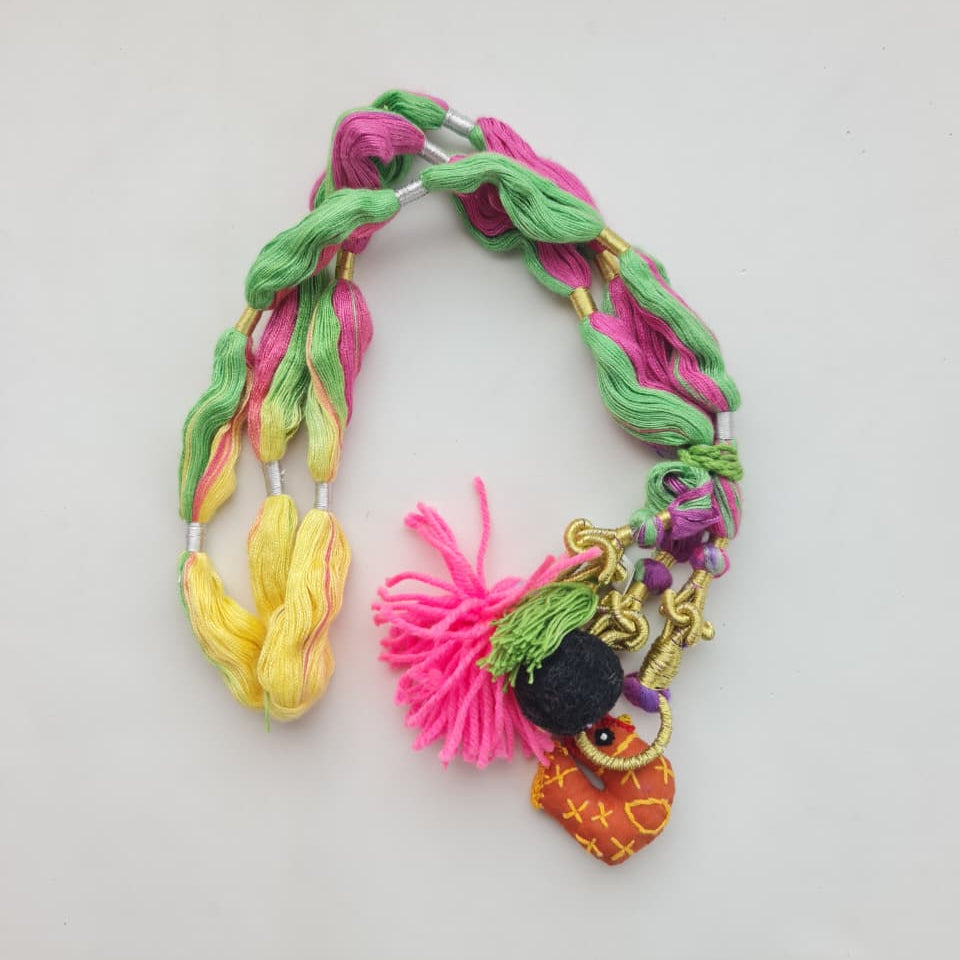A multicolor braided cord or strap with tassels and small decorative charms, photographed on a plain light background.