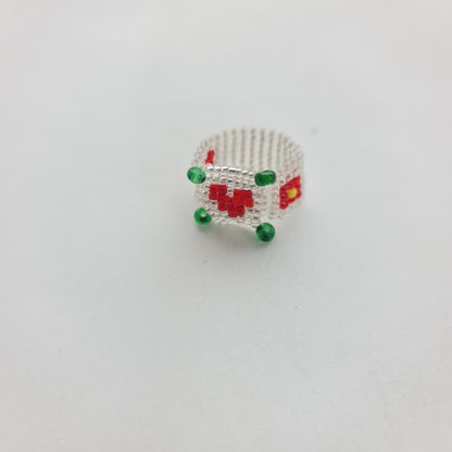 A small silver ring featuring a beaded design with red and yellow details and green bead accents, set against a plain white background.