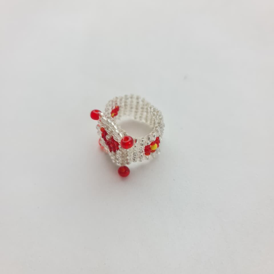 A small silver ring decorated with red and yellow floral beadwork, photographed on a plain white background.