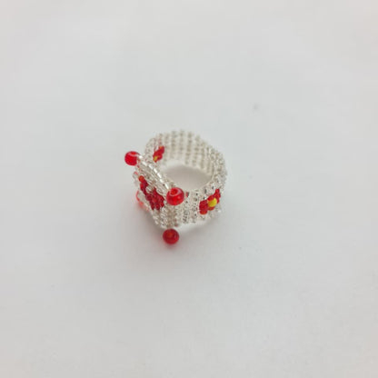 A small silver ring decorated with red and yellow floral beadwork, photographed on a plain white background.