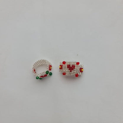 Two small handmade beaded jewelry pieces, one a ring and one a rectangular charm or connector, featuring white seed beads with red and green accents, on a plain white background.
